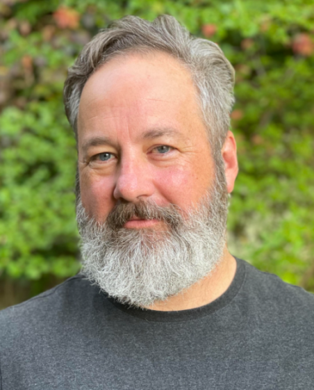 Headshot of Chris Jones, a middle-aged man with a gray beard and graying hair, wearing a dark gray t-shirt.