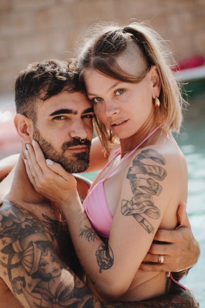 A man and a woman in a pool, embracing and looking at the camera.