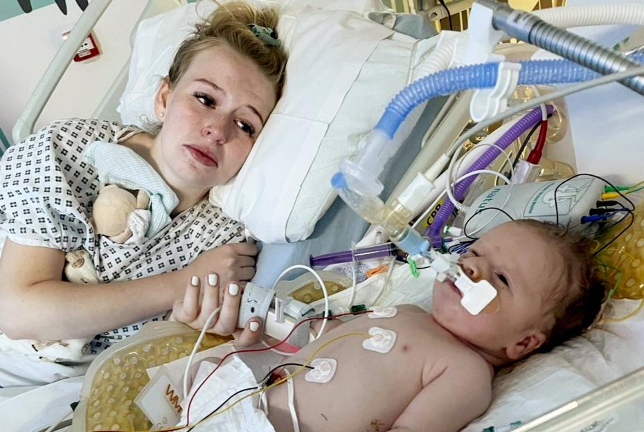 Shanine Skilton-Cole holding the hand of her son Cobie Miles in a hospital bed, where he is hooked up to medical equipment.
