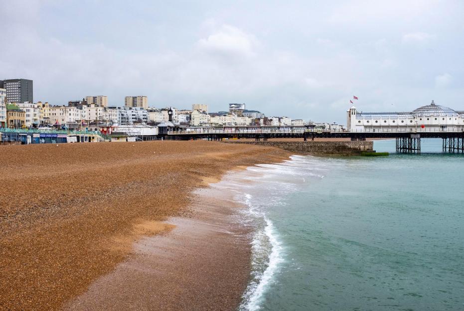 Empty Brighton beach on a rainy summer solstice day, with the Palace Pier extending into the water.