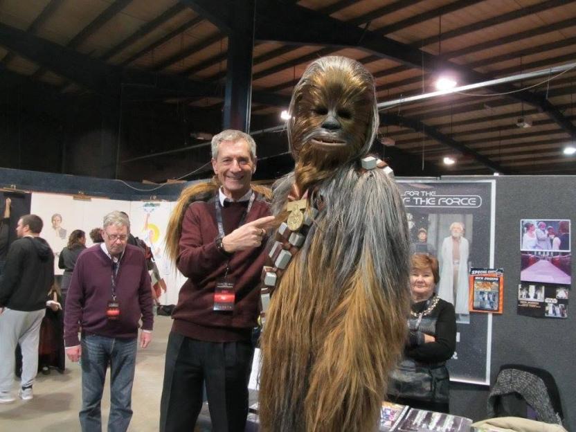 A man in a red sweater points at a person in a Chewbacca costume.