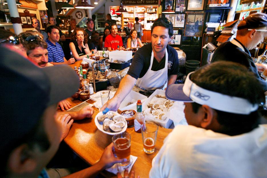 A server handing a plate of oysters to a customer at Union Oyster House in Boston.
