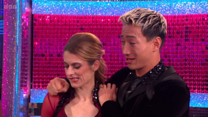 A male dancer with blonde hair and a woman with brown hair dancing on a stage.