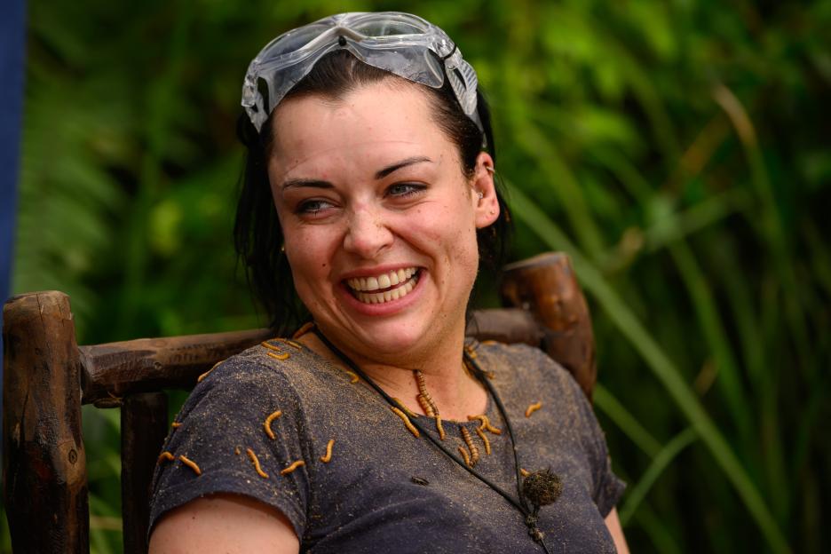 Shona McGarty smiling with goggles on her head, covered in dirt and mealworms.