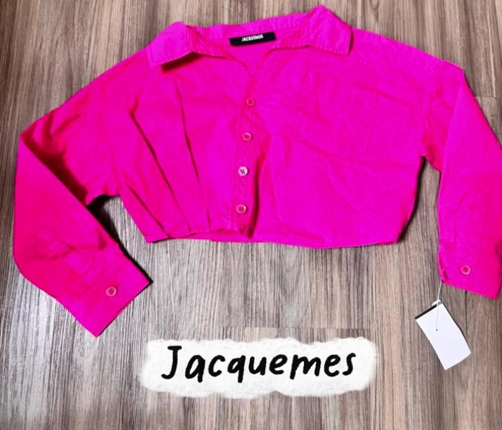 Jacquemus pink cropped button-up shirt on a wooden surface.