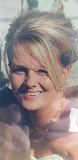 A smiling woman with blonde hair and a pearl necklace.