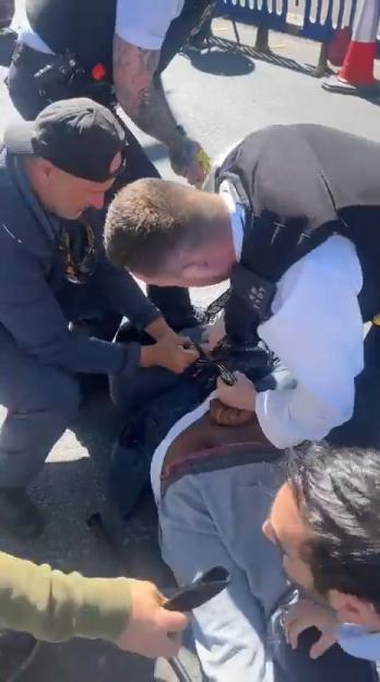 Several men restraining another man on the ground.