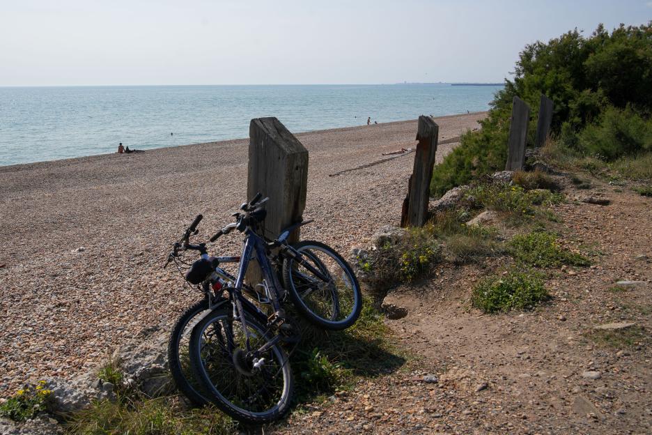 Two bicycles leaning against a post overlooking a nudist beach.