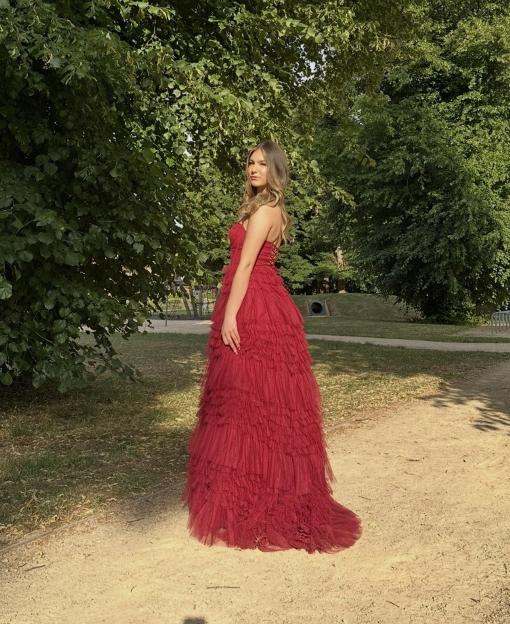 Isabelle Sava, an aspiring lawyer and teen Taekwondo world champion, wearing a red ruffled dress, standing in a park.
