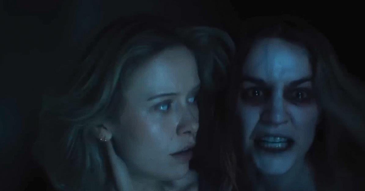 A woman with glowing white eyes looking forward, and behind her, another woman with pale skin and dark eyes screaming, both in the dark.