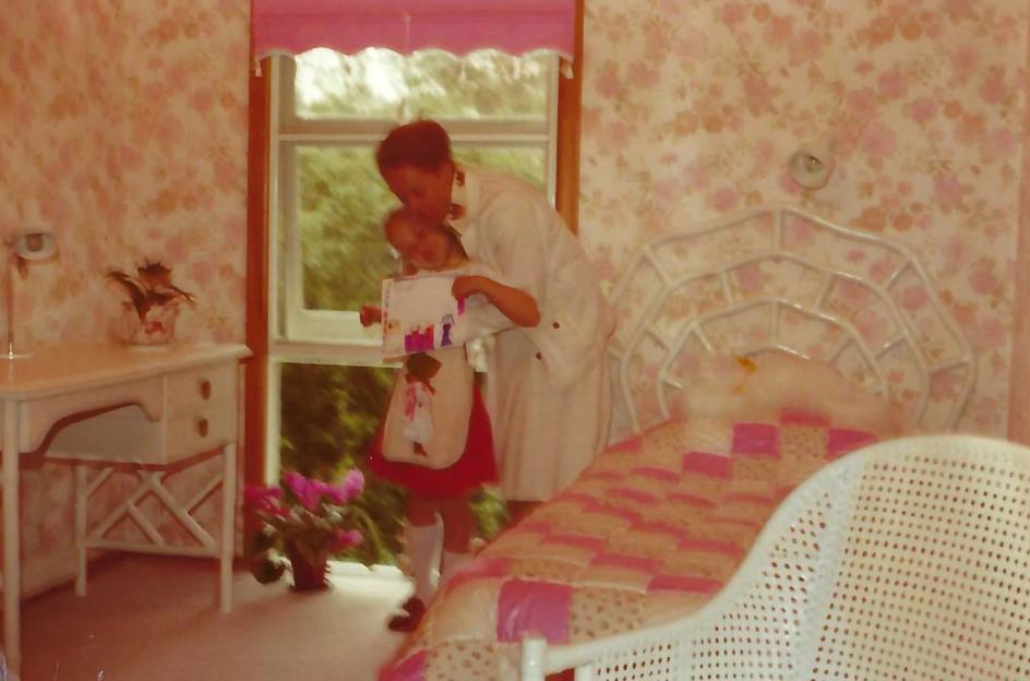 a woman holds a little girl in her arms in a bedroom