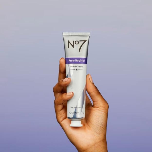 Hand holding a tube of No7 Pure Retinol Hand Cream.