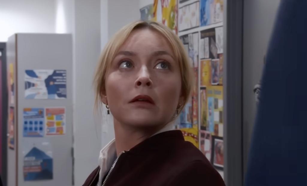 A blonde woman looks up with a surprised expression.
