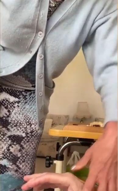 A person in a light blue cardigan and patterned dress tending to someone's hands.