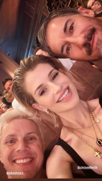 Three people taking a selfie, a woman in the middle, a man to her left, and another man to her right.
