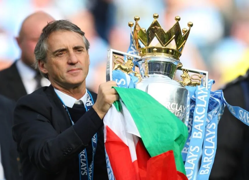 Roberto Mancini holding the Barclays Premier League Trophy and an Italian flag.