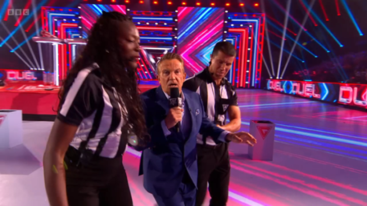Gladiators host Bradley Walsh is escorted out of the arena by two referees.