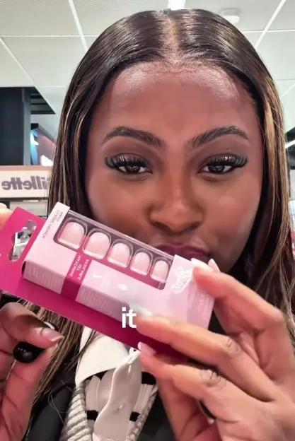 A woman holding a package of press-on nails from Boots.