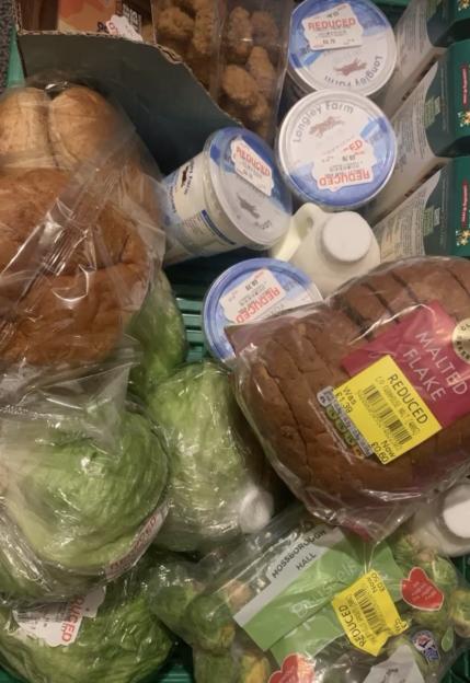 A grocery haul displaying various food items, including malted bread, lettuce, Brussels sprouts, and yogurt pots, many with "REDUCED" stickers showing discounted prices.