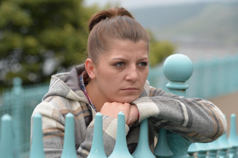 Sarah Wilson, a Rotherham abuse victim, rests her chin on her hands while leaning on a turquoise fence.