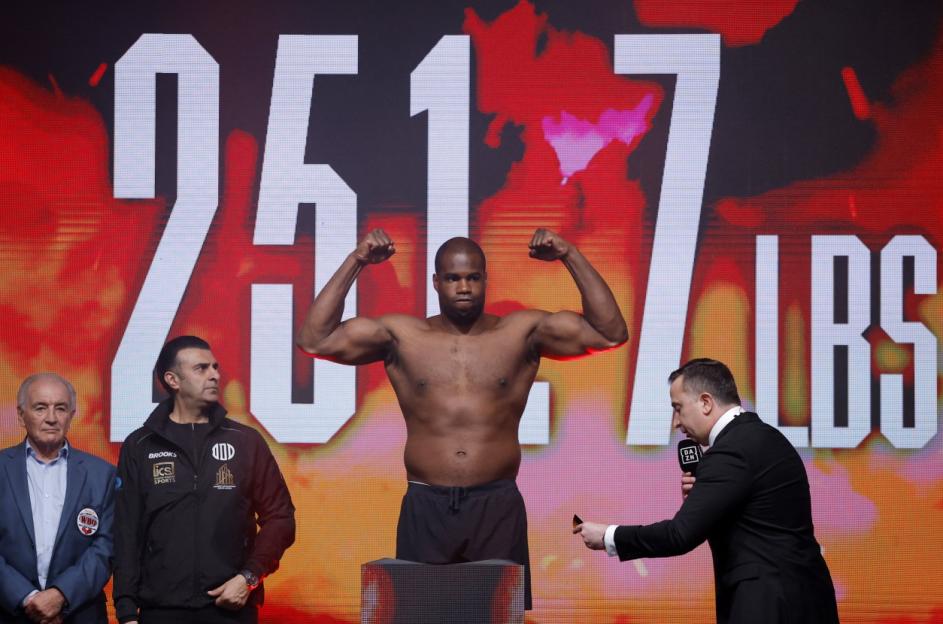 Daniel Dubois flexing his biceps at the weigh-in, with his weight of 251.7 lbs displayed behind him.
