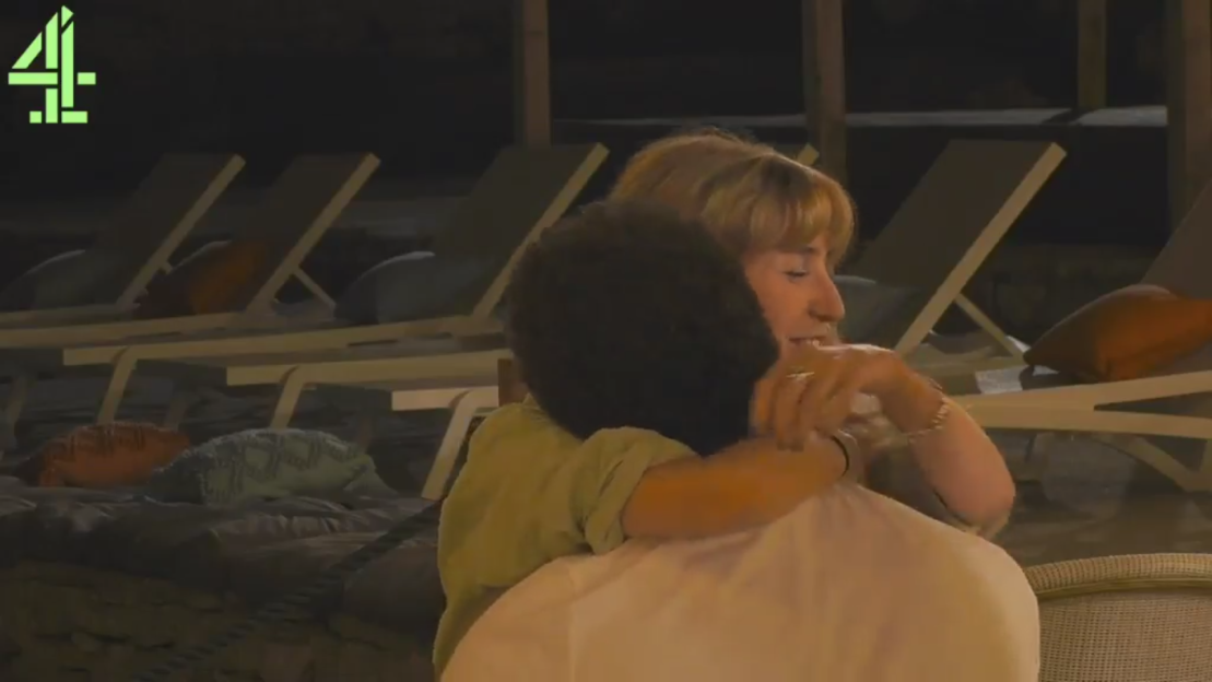 Woman with short blonde hair embracing a person with dark curly hair.