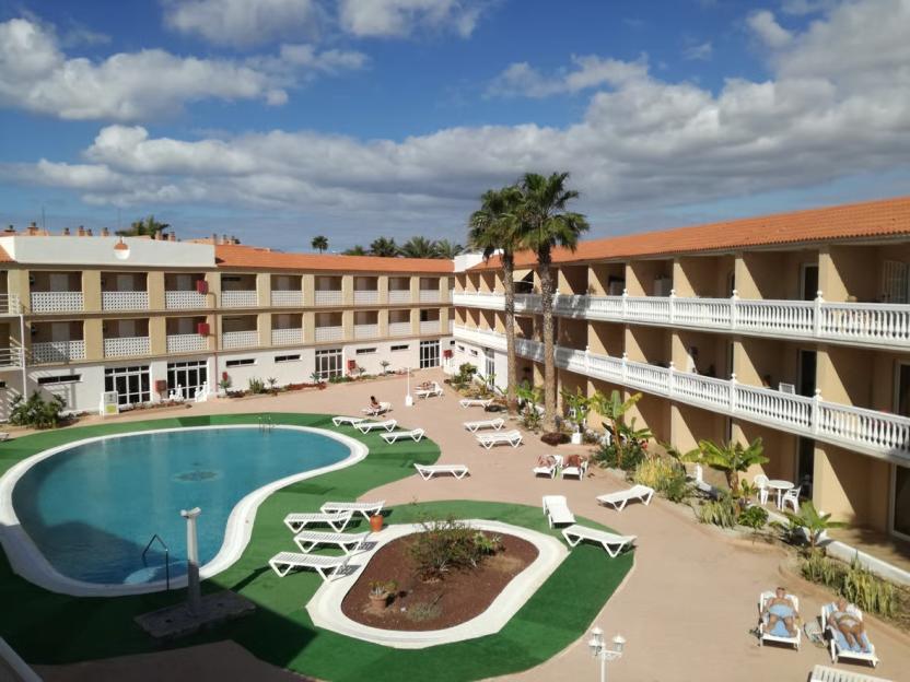 Outdoor view of a hotel complex with a swimming pool and sun loungers.