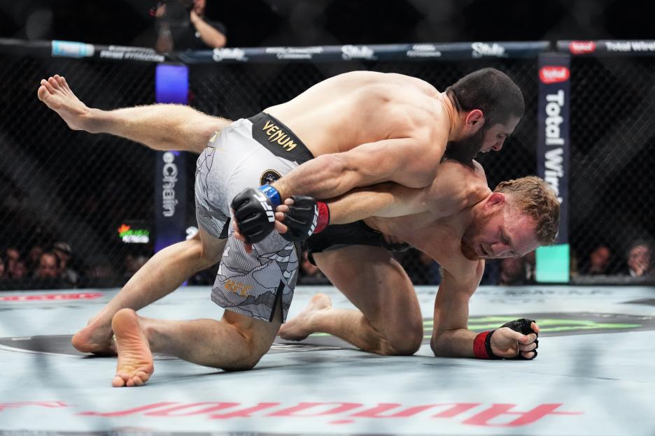 UFC fighters Della Maddalena and Makhachev grapple during a match.