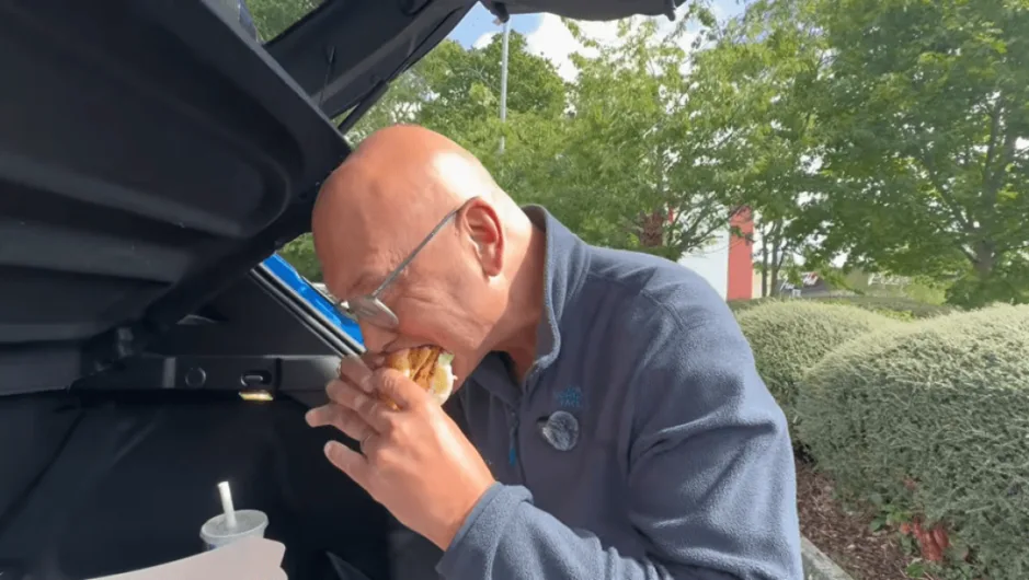 Gregg Wallace eating a burger in the trunk of a car.