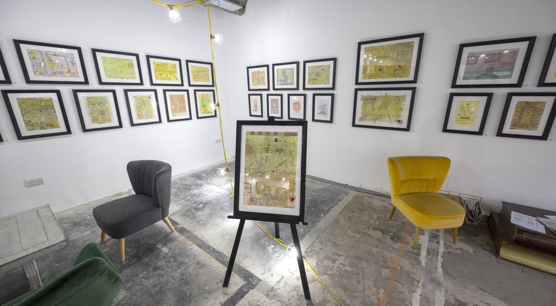 Exhibition of Charles Bronson's artwork at the Lily Selavie Gallery, featuring framed drawings and chairs for viewing.