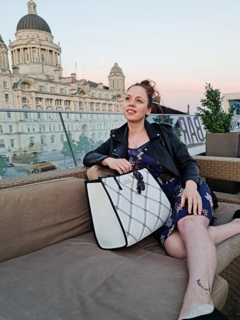 Sindija Virse sitting on an outdoor sofa with a historical building in the background.