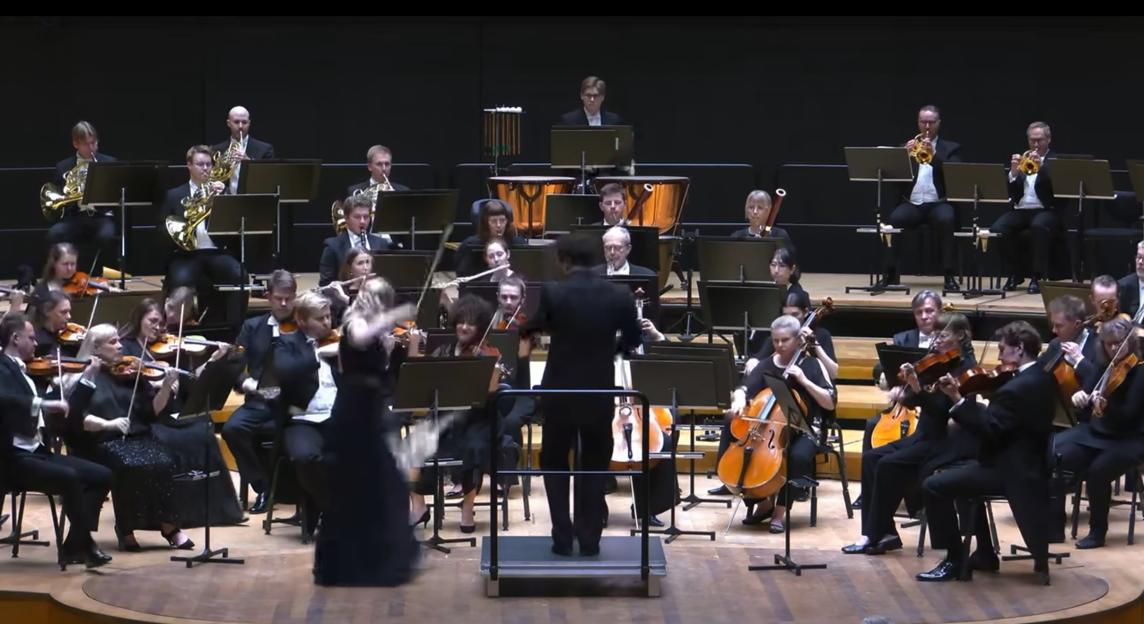 A female soloist's violin is knocked out of her hands by a male conductor's baton during a performance.