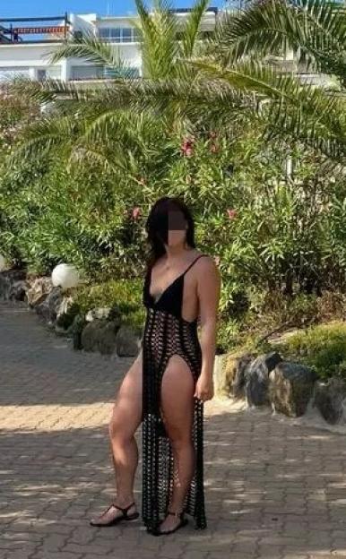 Woman in a black crochet maxi dress on a resort pathway.