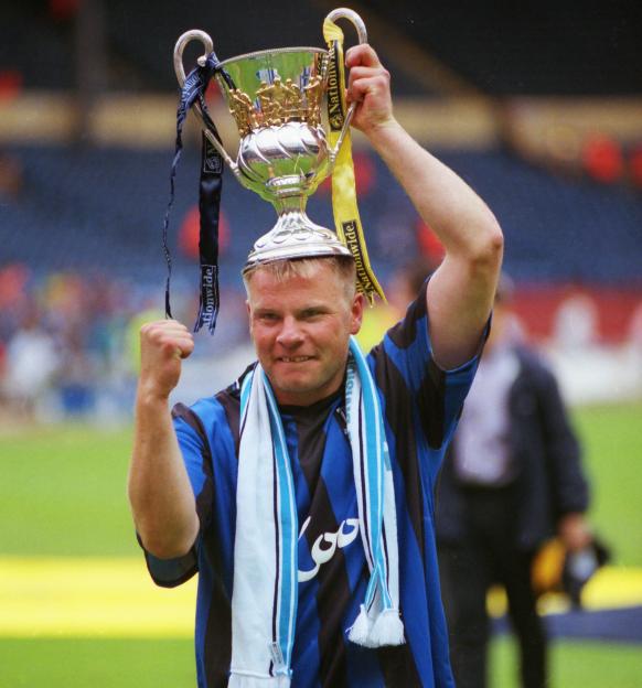 Andy Morrison, Manchester City captain, holding the Playoff trophy overhead.