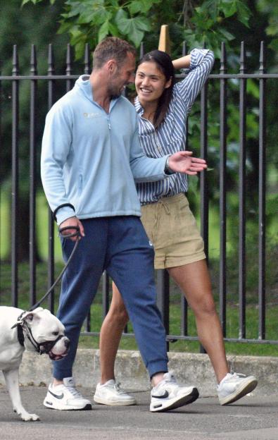 Emma Raducanu walking with a man and a dog in a park.