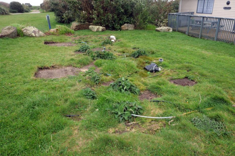 Temporary electrical wiring and equipment running across a grassy area.
