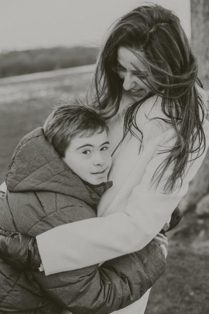 Black and white photo of a woman embracing a boy with Down syndrome.