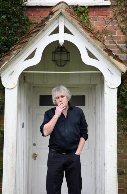 Journalist Rod Liddle smoking a cigarette while standing in a doorway.