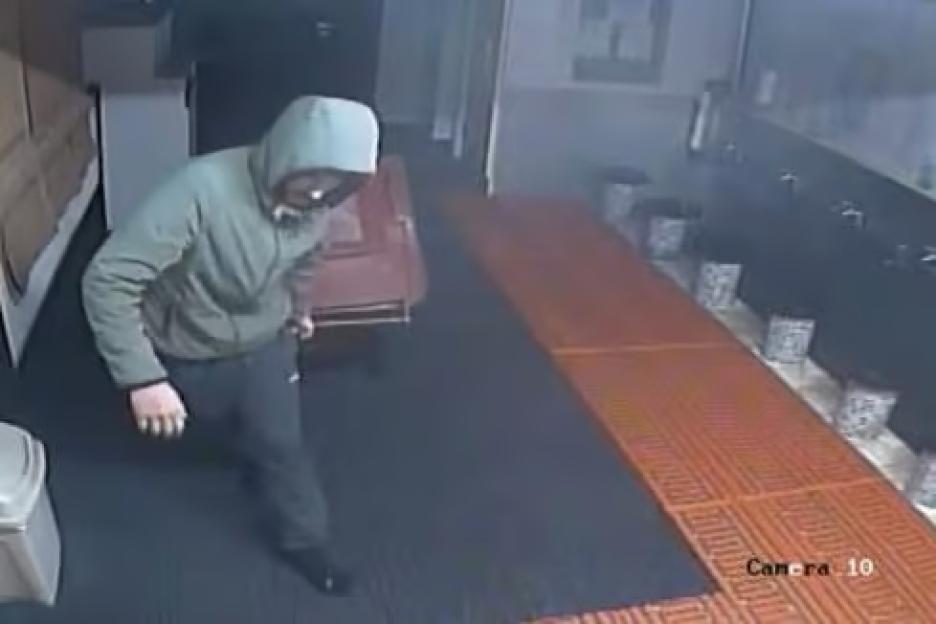 CCTV footage of a burglar wearing a hoodie and dark pants, taking off his shoes before entering a mosque to steal a safe.