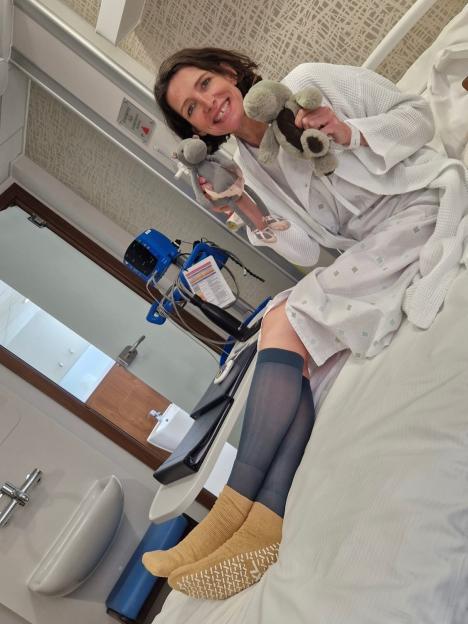 Thomasina Miers smiling in a hospital bed, holding two stuffed animals.