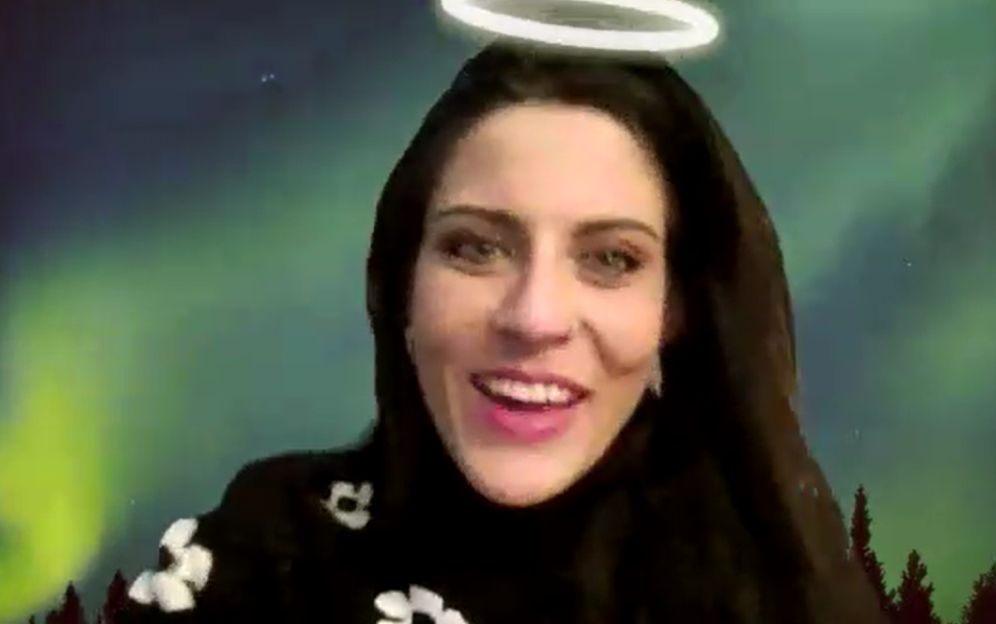 Woman with long dark hair, wearing a dark top, with a halo filter and a backdrop of aurora borealis.