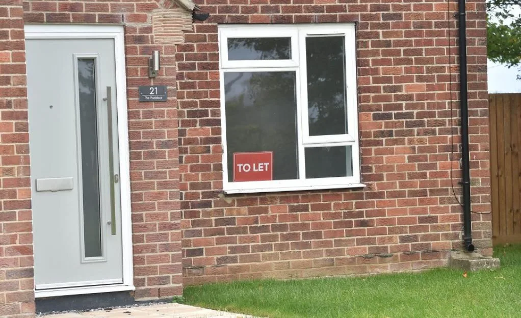 A brick house with a "To Let" sign in the window near the Linton-on-Ouse migrant center site.