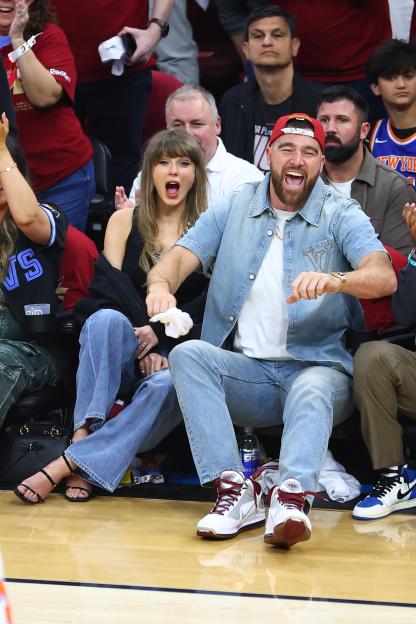 Travis Kelce and Taylor Swift celebrating during a basketball game.