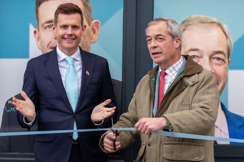Nigel Farage cutting a light blue ribbon with Reform UK candidate Matt Goodwin.