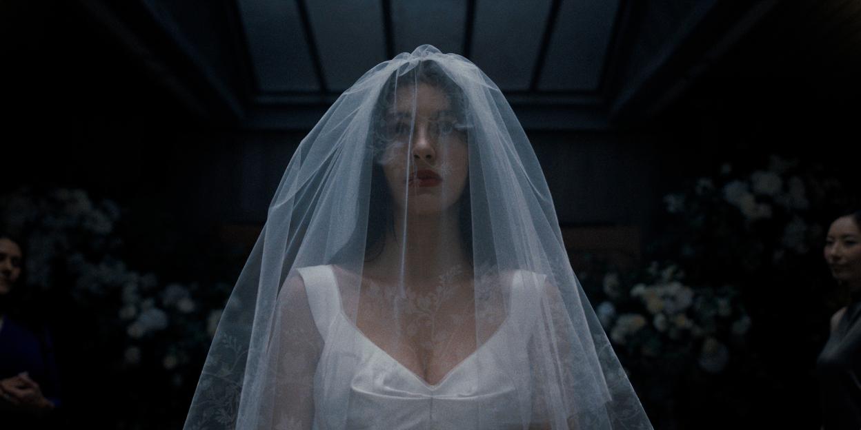Camila Morrone as Rachel Harkin in "Something Very Bad Is Going to Happen", wearing a white wedding dress and veil.