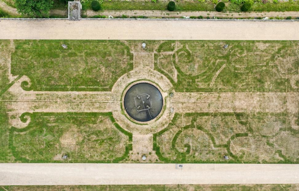 Aerial view of a garden showing the outline of an ornate 17th-century flower bed design revealed by drought-stressed grass.