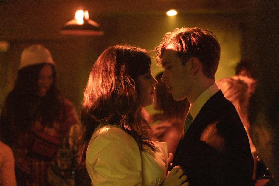 Annie and Robert from the show "Industry" looking at each other in a dimly lit setting.