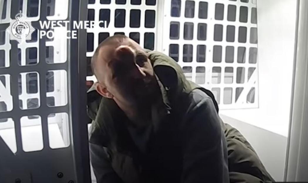 Matthew Jonathan, 39, in the back of a police transport vehicle.