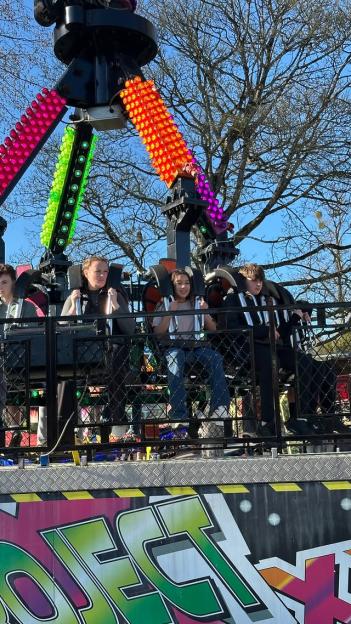 Helen Flanagan and her children, Matilda, Delilah, and Charlie, on a spinning carnival ride with colorful lights.