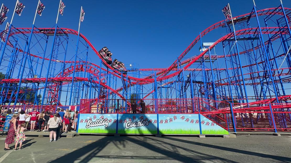 The Bulldog Coaster at Brean Theme Park, with red tracks and blue supports, and a queue of people waiting to ride.